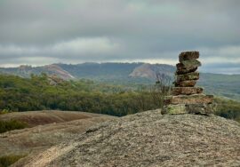 A small stack of balanced stones on a granite outcrop overlooking hills