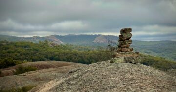 A small stack of balanced stones on a granite outcrop overlooking hills