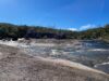 Creek water flowing across a broad granite slab under a blue sky