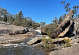 Granite boulders of different shapes and sizes beside a flowing creek