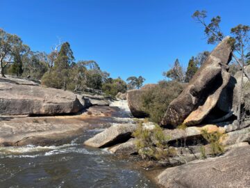 Granite boulders of different shapes and sizes beside a flowing creek