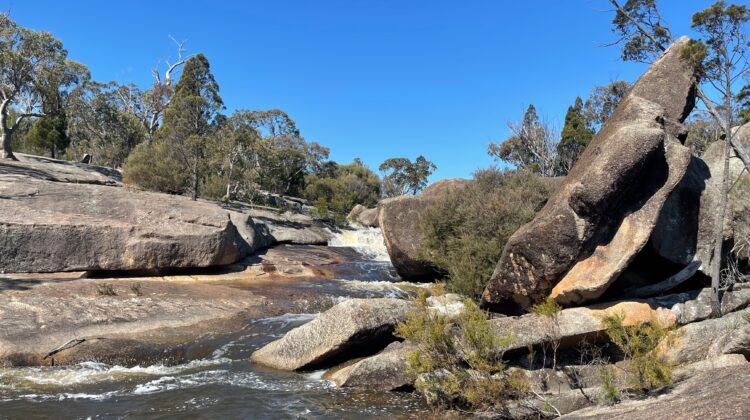 Granite boulders of different shapes and sizes beside a flowing creek